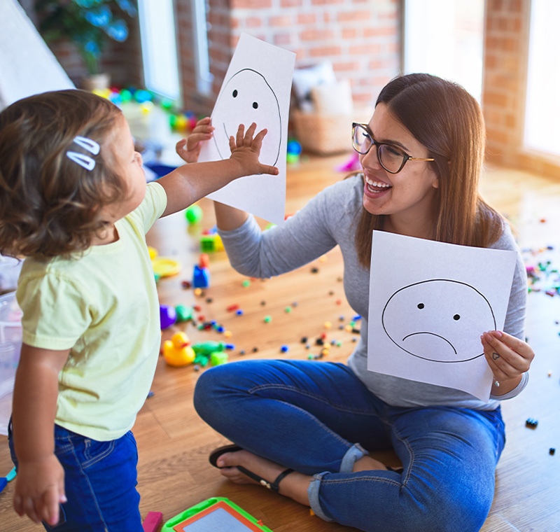 A behavior technician specialist works one-on-one with a child during a learning activity, providing guidance and positive reinforcement in a supportive therapy environment.