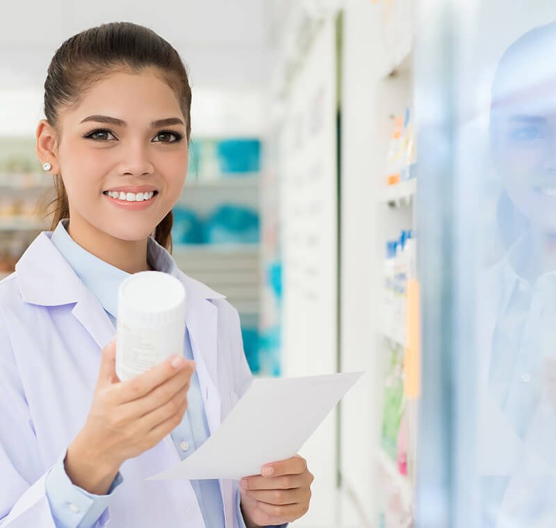 A pharmacy technician professional in a white lab coat organizes prescription medications on pharmacy shelves and verifies labels to ensure accuracy and patient safety.
